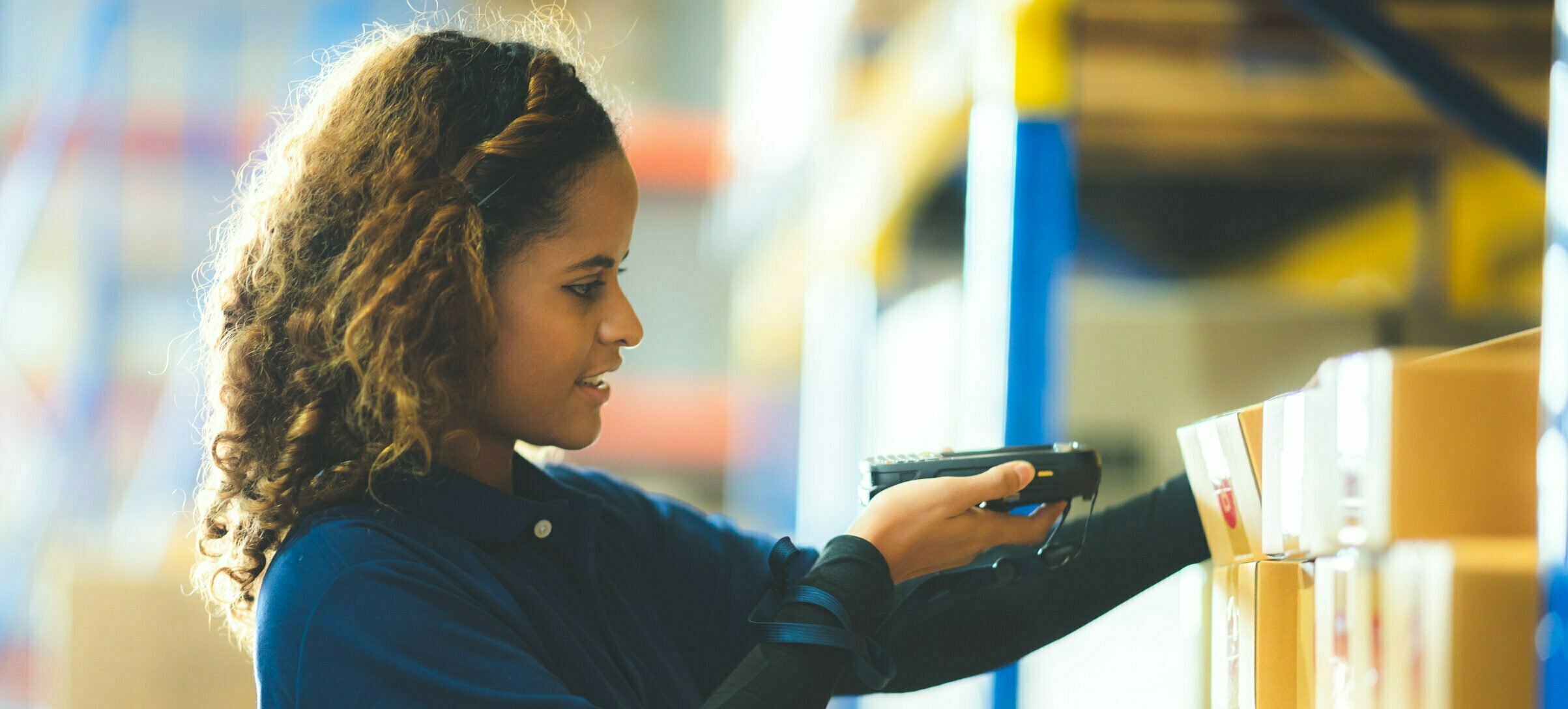 Warehouse worker using bar code scanner to analyze newly arrived goods for further placement in storage department, working at distribution centre..